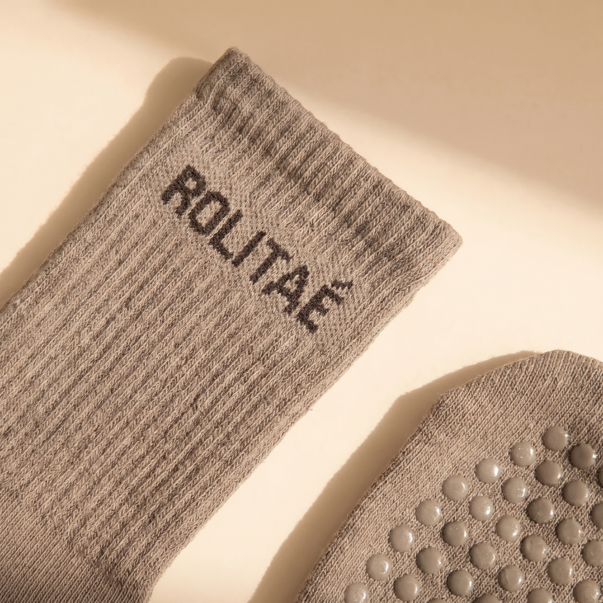 De mocha pilates sokken uit het triple pack groen, mocha en bruin, close-up van de boord met logo en de grip