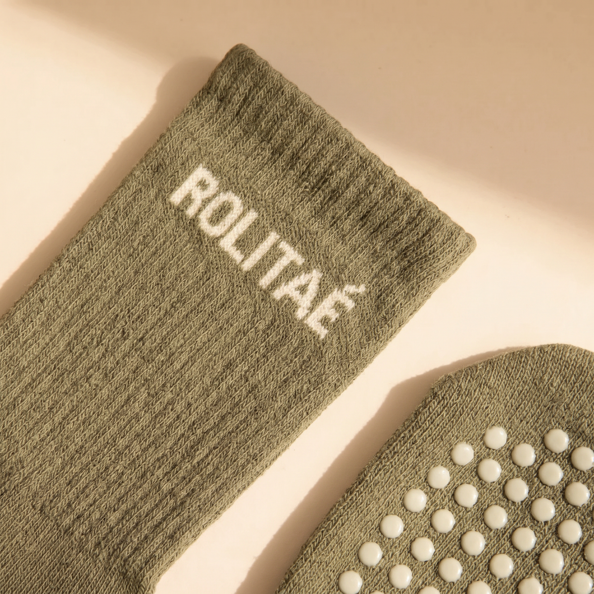 De groene pilates sokken uit het triple pack mocha, groen en baby blauw, close-up van de boord met logo en de grip
